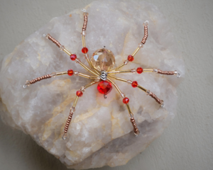 Golden beaded wire spider featuring warm amber tones, red crystal beads, and shimmering metallic details for unique boho décor.